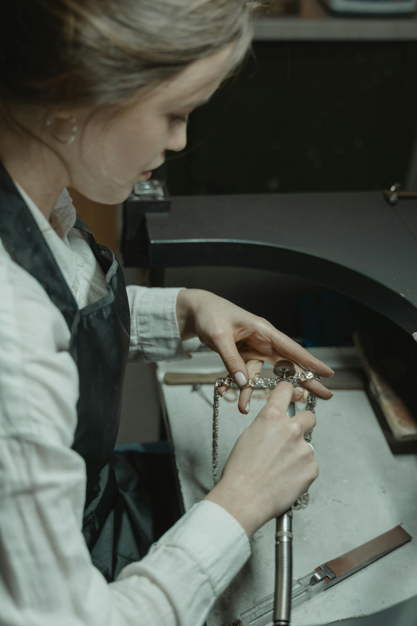 Focused artisan crafting a silver necklace in a professional jewelry workshop.